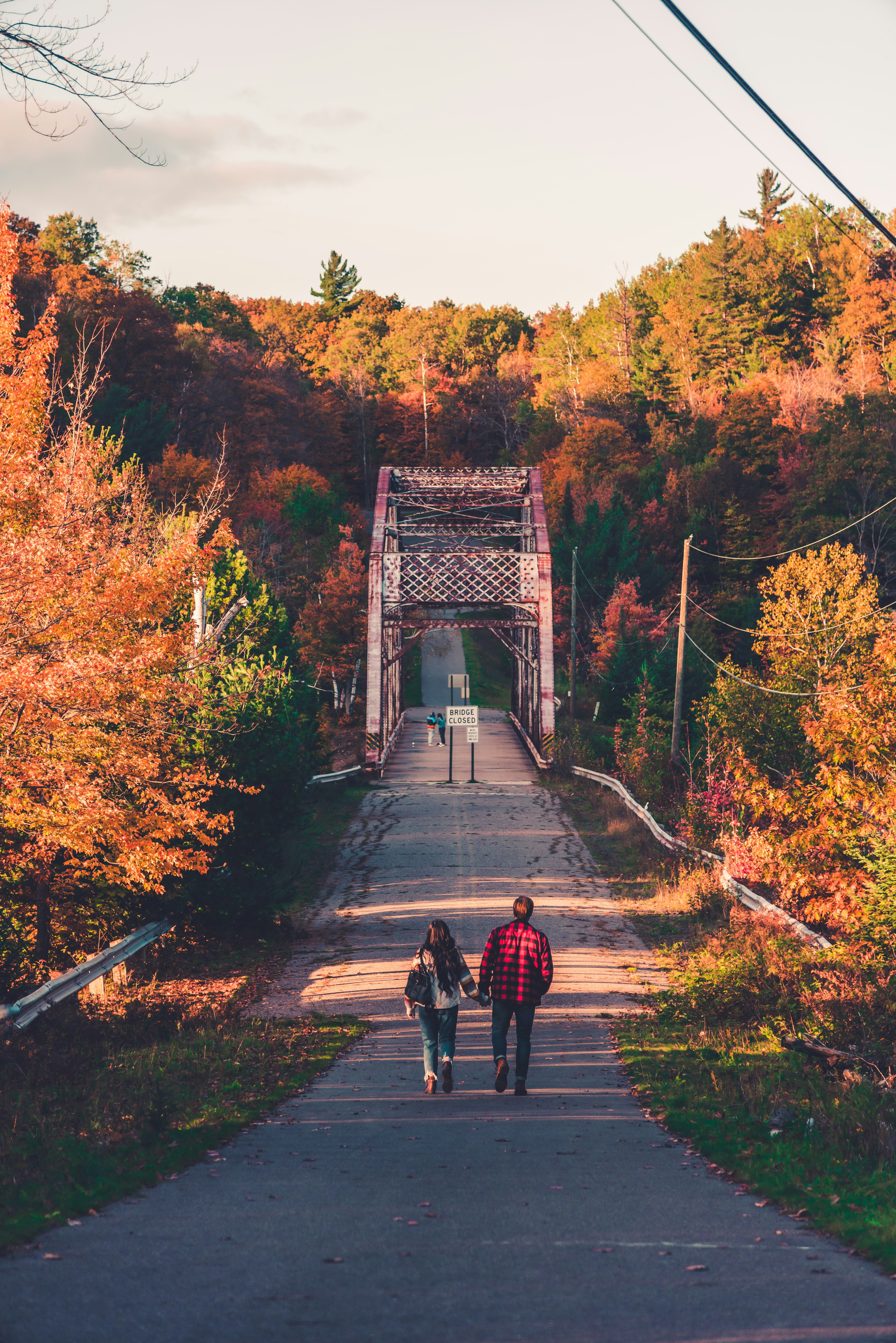 man in red jacket and black pants walking on bridge